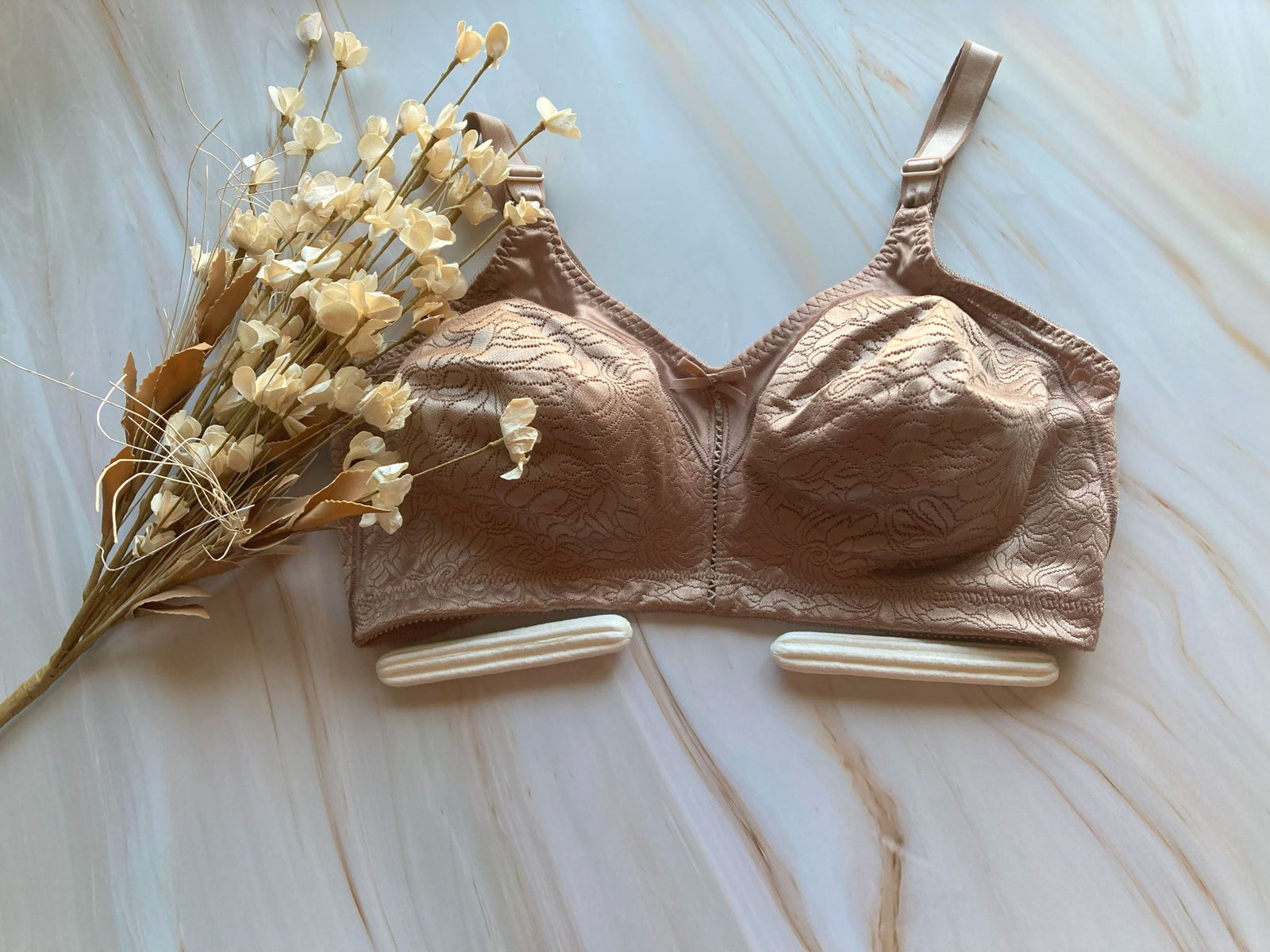 A brown bra with two Breast Buddies pads and flowers.